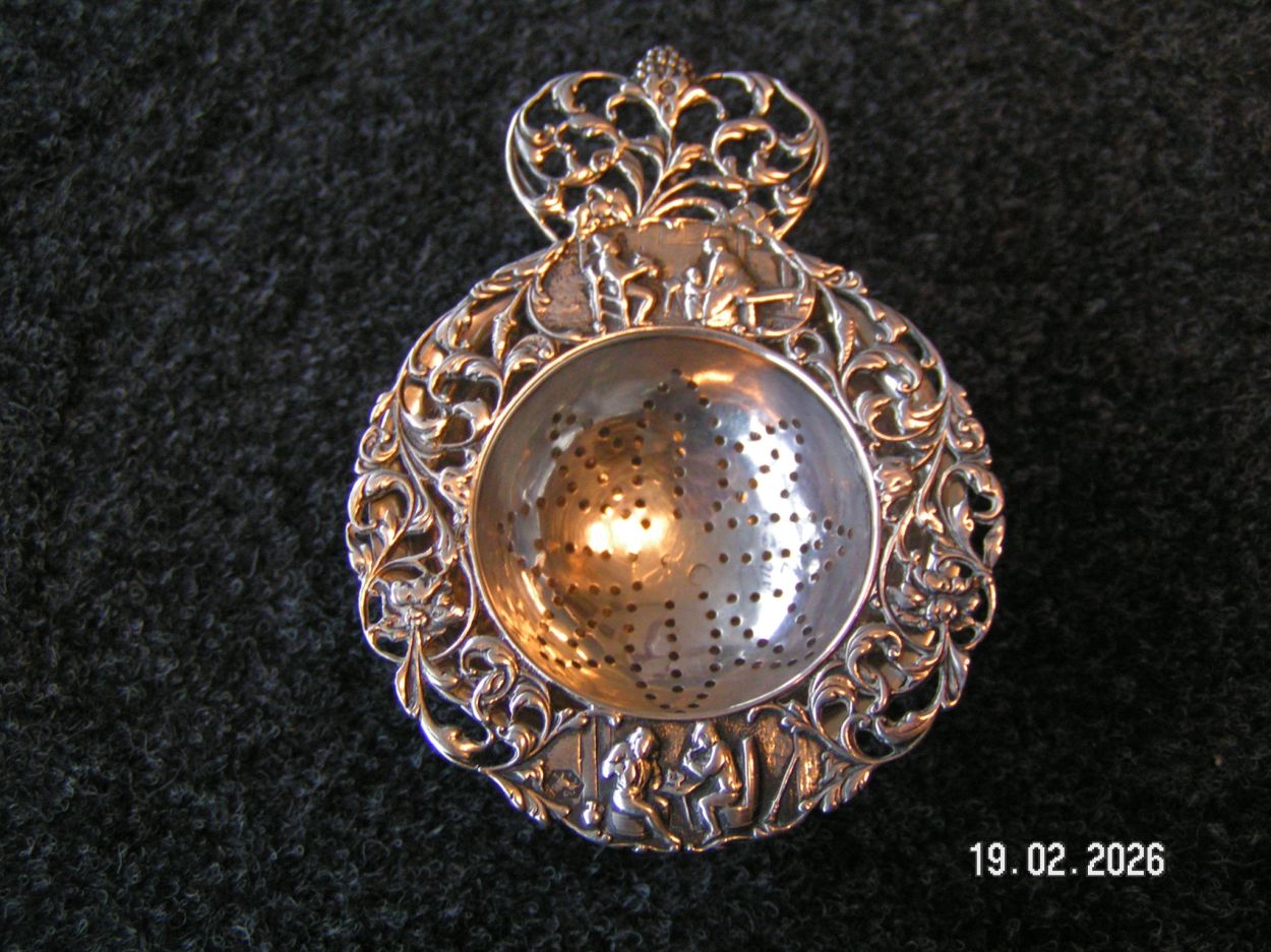 artikelnr. 1602083 Antieke Zilveren Thee Zeef, met Ornamenten in Uitmutende Staat en Gemerk Tweede Gehalte. prijs €125,- euro
